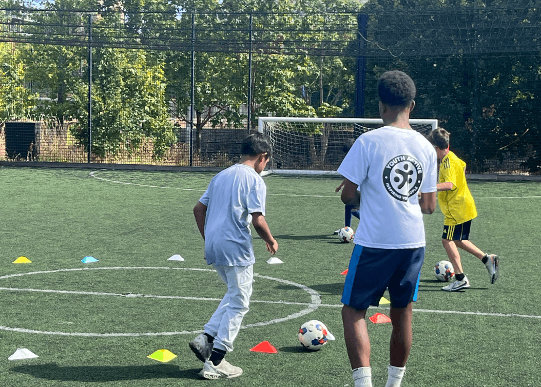 A Youth Active coach running a football drill with young players