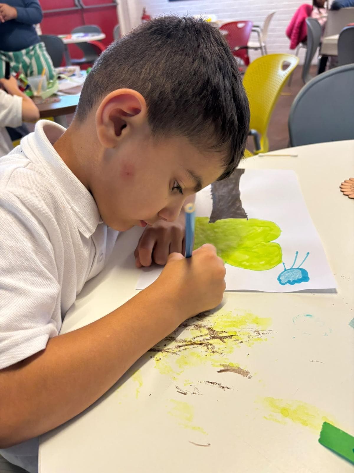 A young member concentrating while painting a nature-themed picture at Youth Active