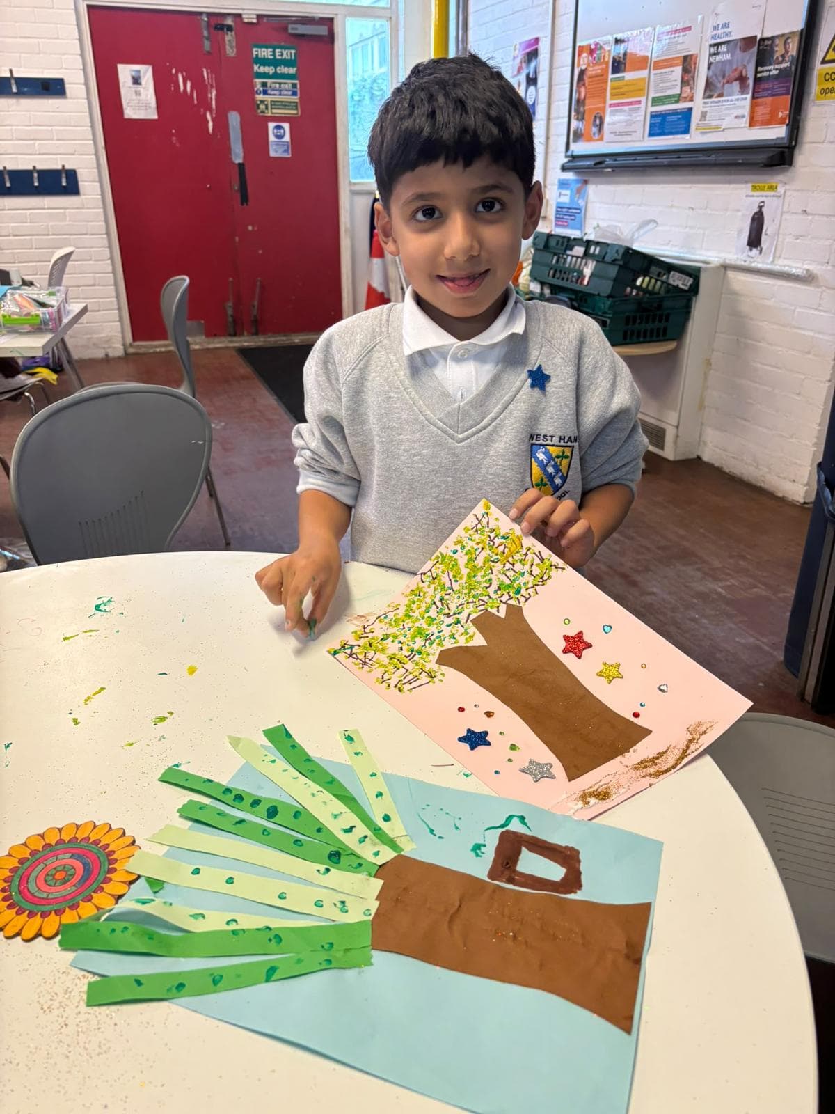 A young member proudly holding up their finished nature-themed tree artwork