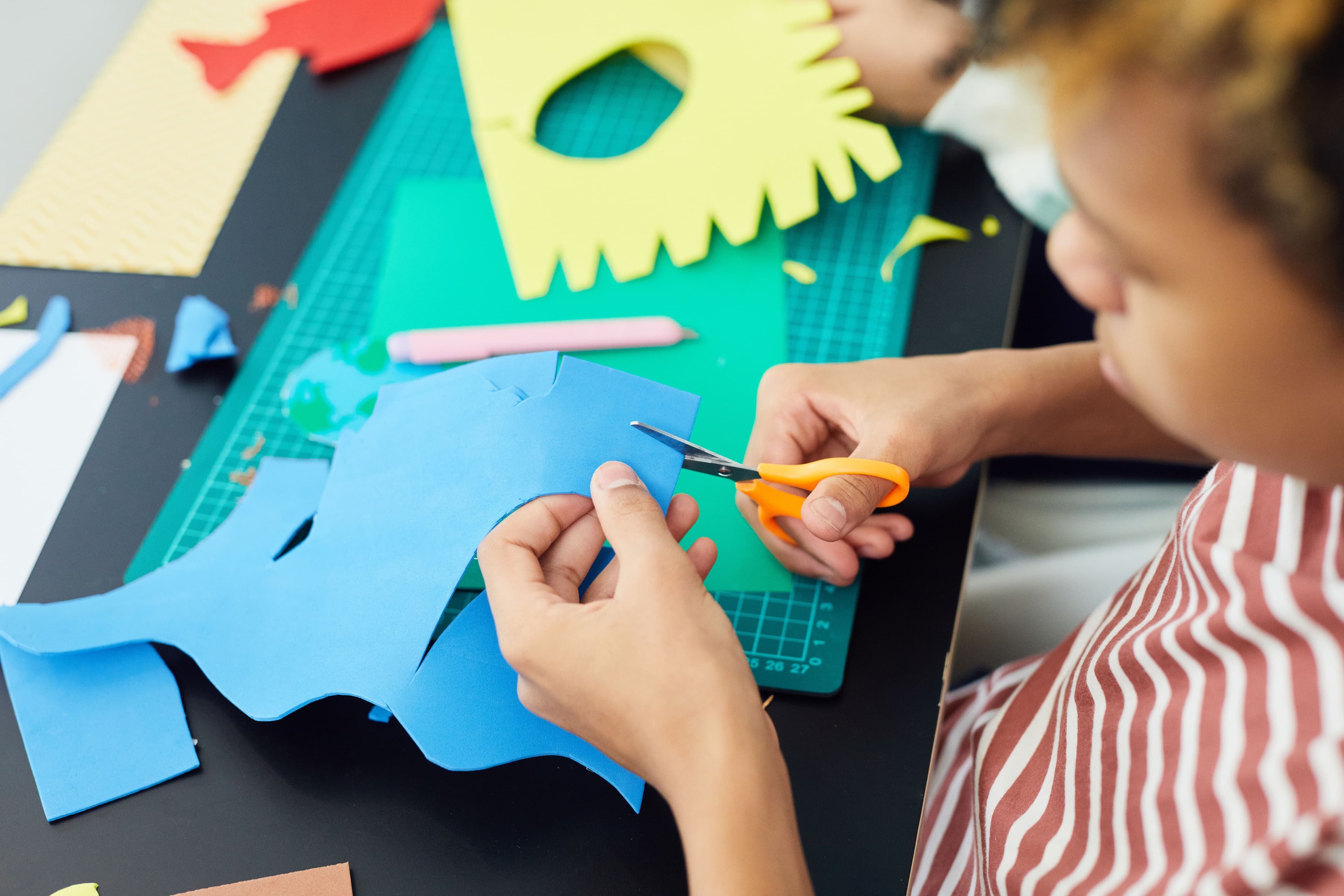 Young person cutting colourful paper at Youth Active arts and craft session
